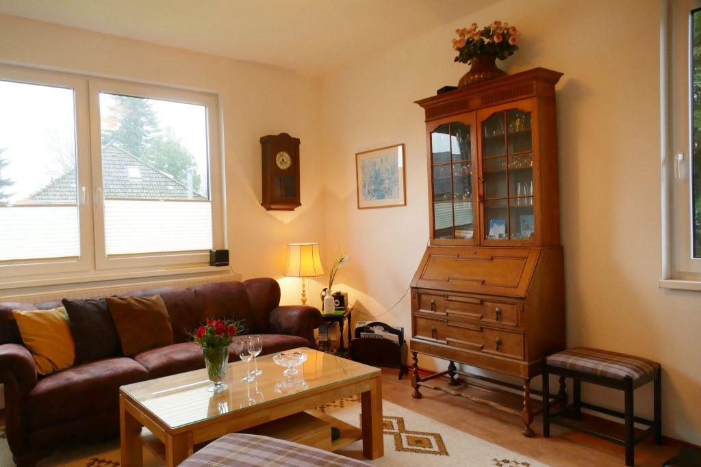 Ferienwohnungen-Hofmann - Untergeschoss, Gebäude innen, gemütliche Sitzecke, Rosen und Gläser auf Tisch, Vitrine, Wohlfühlen in Ostfriesland, Friesland, Urlaub auf dem Land, Urlaub in Friesland, Ferien im Gulfhof