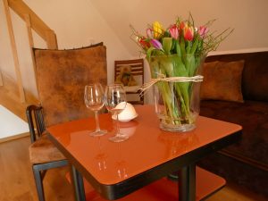 Ferienwohnungen-Hofmann - Obergeschoss, Gebäude innen, gemütliche Sitzecke, Tulpen und Gläser auf Tisch, Wohlfühlen in Ostfriesland, Friesland, Urlaub auf dem Land, Urlaub in Friesland, Ferien im Gulfhof